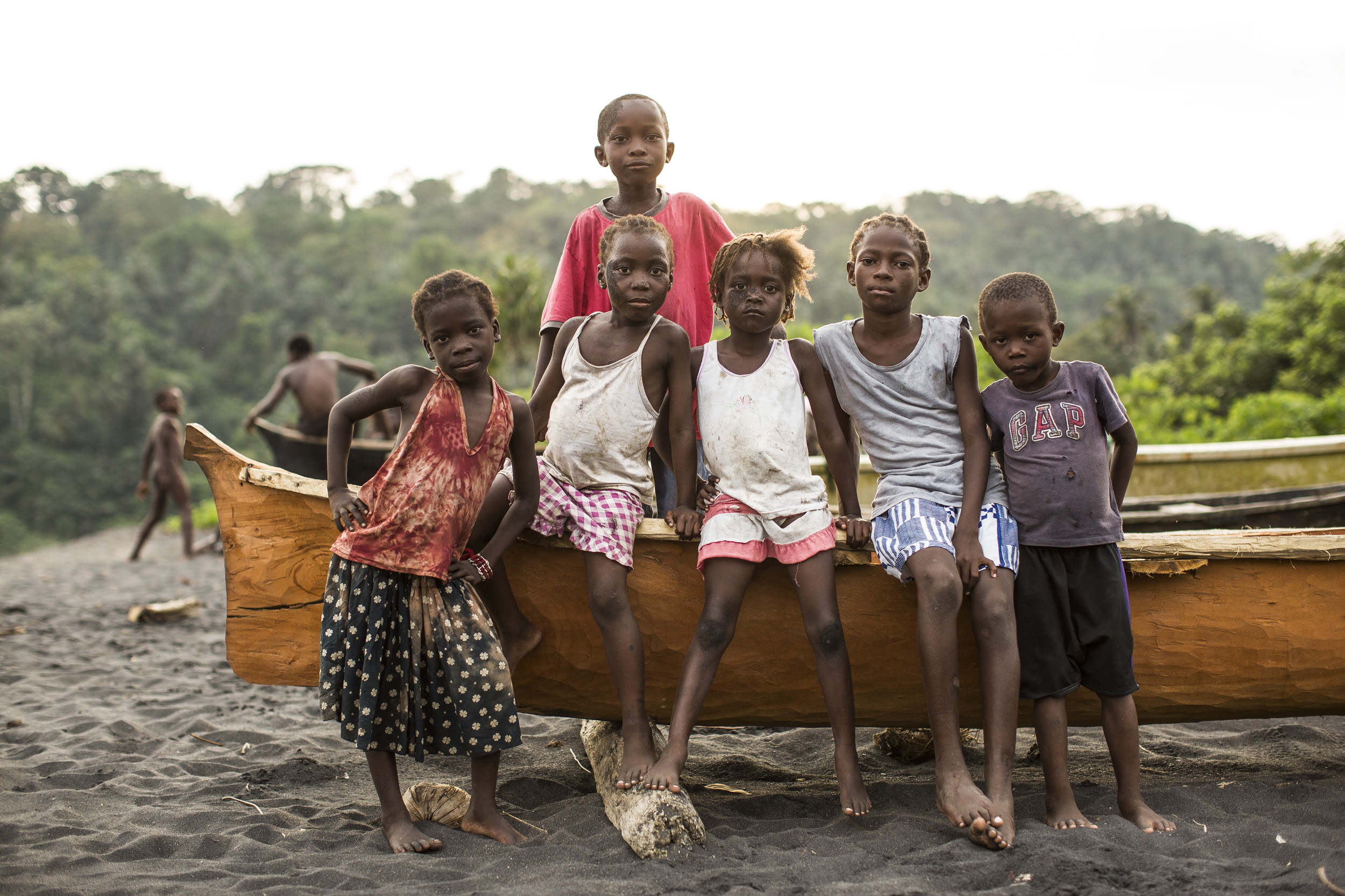 Crianças santomenses numa praia com canoa tradicional - vida autêntica local